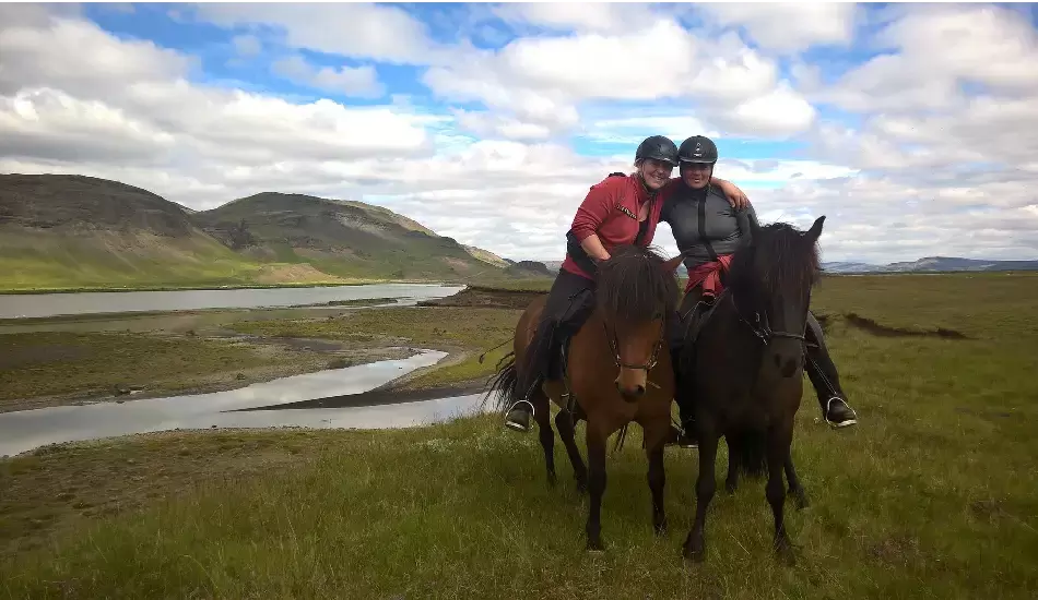 Two riders on horseback having an arm around each other.