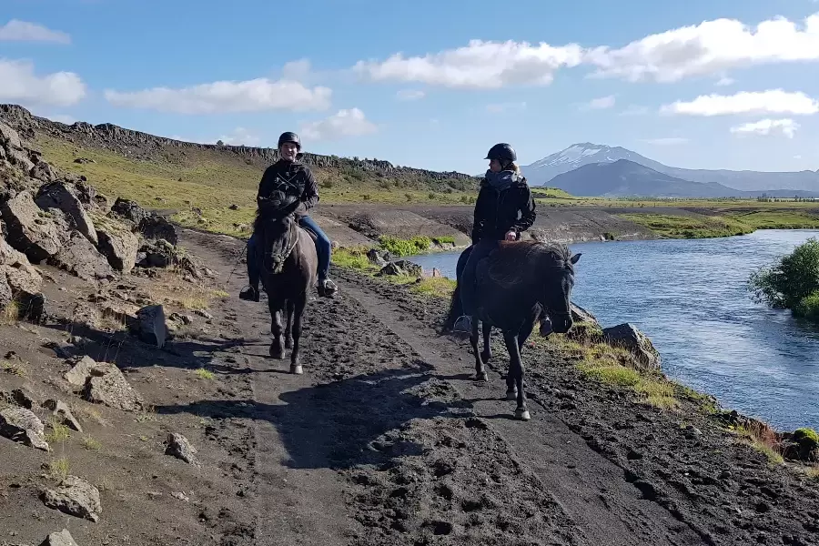 Two riders on Icelandic horses in front of the volcano Hekla